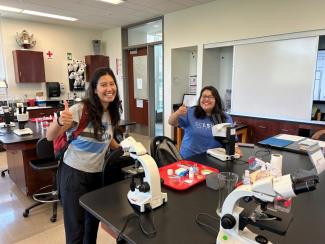 Two plant biology TAs giving a thumbs up and smiling