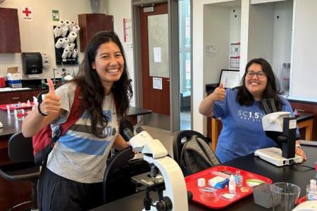 Two plant biology TAs giving a thumbs up and smiling